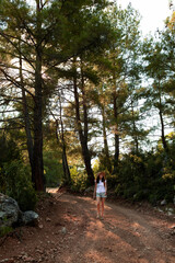 Fototapeta na wymiar a traveler girl with a backpack walks along a forest road.