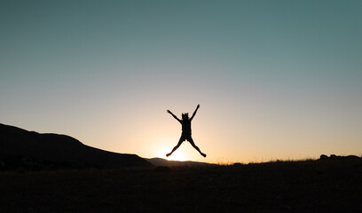 girl jumping at sunset in the mountains