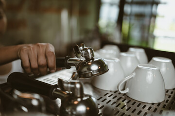 Fototapeta na wymiar barista pick coffee bottomless portafilter to make a coffee at cafe. Coffee maker concept.