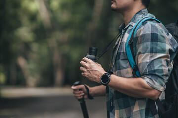 Hikers use binocular to see animals and view landscape  with backpacks walking through on the road in the forest. hiking and adventure concept.