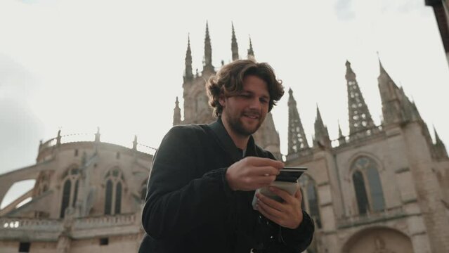 Young man tourist taking polaroid photo of girlfriend in Burgos, Spain