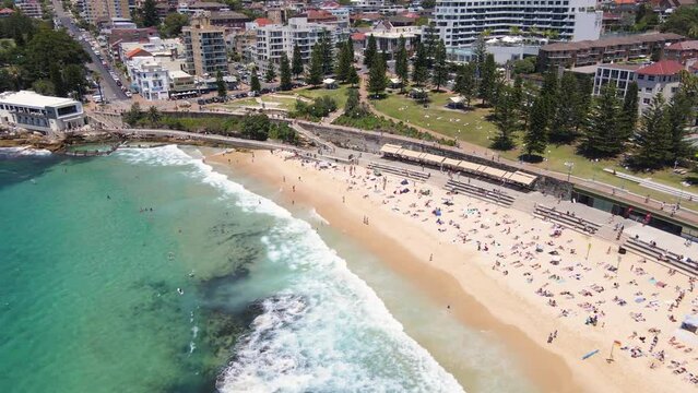 Aerial drone pullback reverse view of iconic Coogee Beach in Sydney, NSW Australia on a sunny day in January 2023   