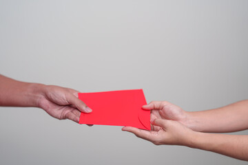 Obraz premium People hand giving Chinese red envelope, money gift for happy Lunar New Year holiday