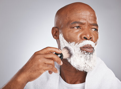 Face, shaving cream and black man with brush on beard, skincare spa treatment on grey background. Health, mock up and facial hair, mature man morning shave routine with space for product placement.