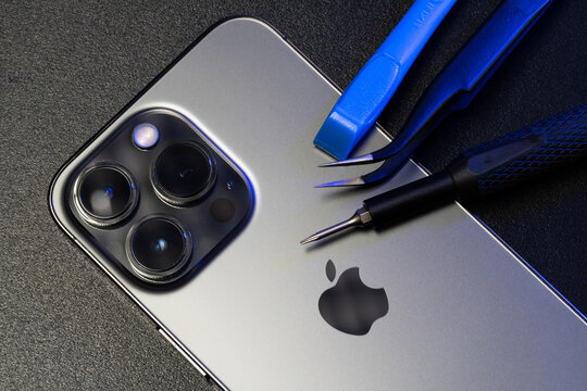 Repair tools on top of Apple iPhone Pro. Screwdriver and Tweezers