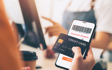 Hand holding credit card payment and using smartphone with scan barcode for discount code coupon,...