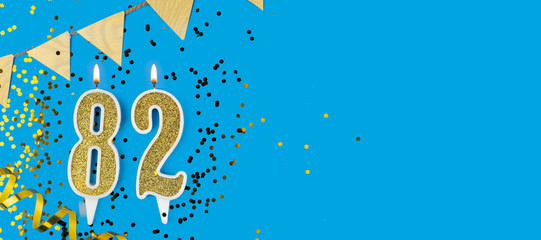 Golden candle number eighty two. Birthday or anniversary card with the inscription 82 on blue background. Anniversary celebration. Banner.