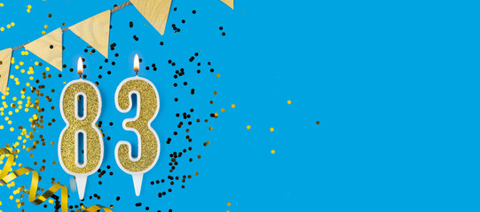 Golden candle number eighty three. Birthday or anniversary card with the inscription 83 on blue background. Anniversary celebration. Banner.