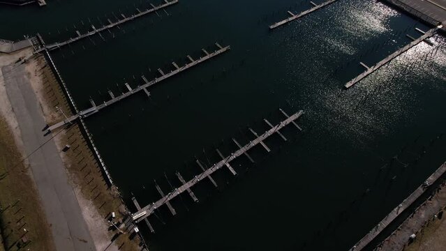An aerial view over an empty marina in Freeport, NY on a sunny day. The drone camera dolly in and tilt down showing the dark green, glistening waters.
