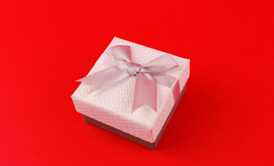 White gift box with gray ribbon on red background