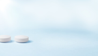 Two white pills lying on a blue table.