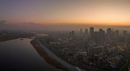 Fototapeta na wymiar Hazy sunrise over high rise buildings in sprawling city next to river