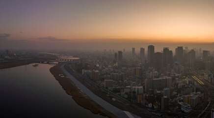 Hazy sunrise over high rise buildings in sprawling city next to river
