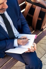 Unrecognizable businessman taking notes in notepad in city