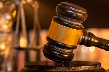 Symbolbild Justiz, Rechtsprechung, Gerichtsurteil: Nahaufnahme von einem Richterhammer, im Hintergrund die Waage der Justitia