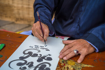 Vietnamese scholar wearing Ao Dai writes calligraphy. Calligraphy festival is a popular tradition...