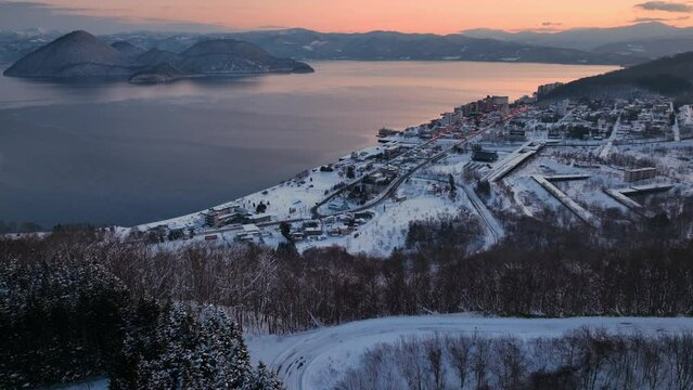 Northern nature landscape of a lake in winter at sunset. Amazing winter lake Toya in Hokkaido, Japan, sunrise. Aerial view of scenic frozen mountain lake 