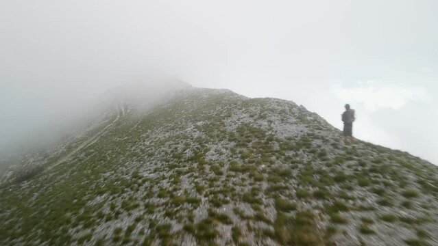 aerial view of man alone lost on mountain ridge with vegetation, Montenegro. fog moving quickly.