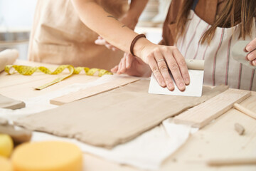 Friends with aprons in a pottery workshop preparing clay to create pieces. Crafts class.