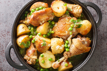 Chicken pieces with potato wedges and roasted in a lemon garlic white wine sauce close-up in a frying pan on the table. Horizontal top view from above