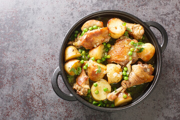 Chicken Vesuvio is pan-seared and baked chicken, potatoes, and peas with a ridiculously delicious herbed wine sauce close-up in a frying pan on the table. Horizontal top view from above - obrazy, fototapety, plakaty