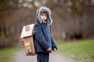 Little child, blond boy with pet dog, carying home on his back, kid, having paper house