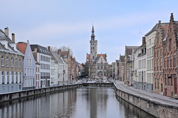 Fototapeta premium Old medieval houses and Poortersloge tower along a canal in Bruges