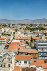 Top view of the Turkish part of Nicosia. Traditional architecture and mosques with minarets against the backdrop of mountains with a flag and a blue sky. Vertical.