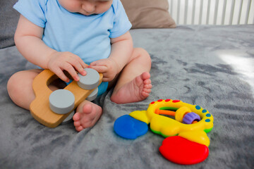 The child plays with a wooden car on the bed.