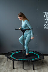  fitness woman in sportswear doing exercises on a sports trampoline in the gym near the wall.