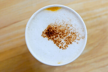 Top view of cappuccino milk foam topped with cocoa power isolated on wooden background, coffee smell and atmospher make fresh good start for morning mood.