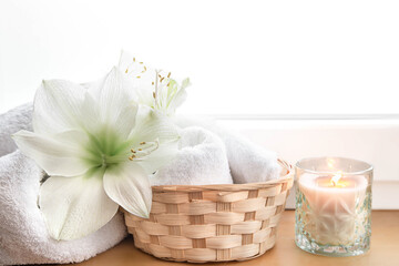 Spa composition with lily flowers and towels in a basket.