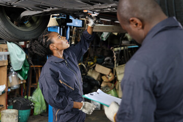 Group of car mechanic in uniform checking maintenance a lifted car service with clipboard at repair...