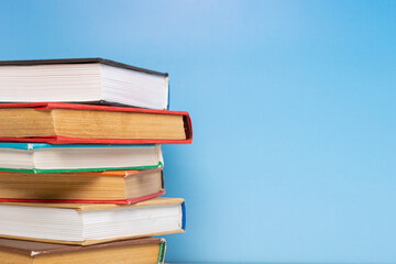 Stack of books in the colored cover lay on blue backround. Education learning concept