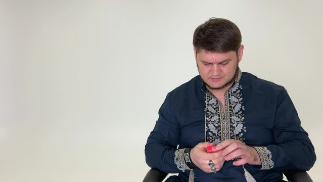 man in a blue shirt straightens his hair brings a card to the pipe and smokes inhaling smoke on his hands he has rings blue eyes beard lets out a puff of smoke there is a place for text