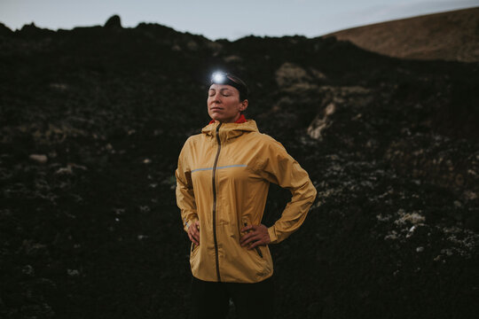 Woman wearing headlamp standing with eyes closed at Caldera Blanca volcano, Lanzarote, Canary Islands, Spain