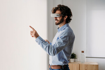 Businessman wearing VR glasses touching transparent screen in office