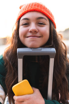 Smiling girl leaning face on suitcase handle