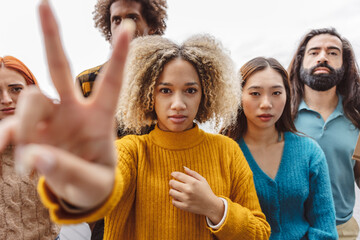 Woman showing peace sign with diverse protestors