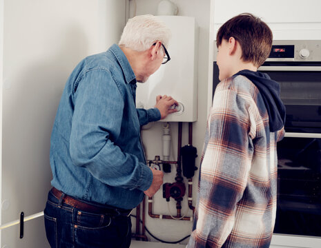 Grandson and grandfather adjusting boiler for energy saving at home