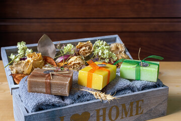 Handmade soap with towels and dry plants on a wooden surface