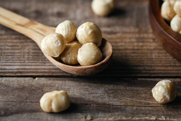 Peeled hazelnuts in a wooden spoon, close-up.