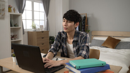 happy Asian male korean student learning from home on the laptop in bedroom