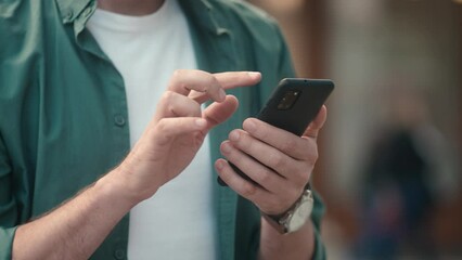 Close-up view of attractive young caucasian man's hands using smartphone online checking social media making internet payments. Focused modern adult male typing texting scrolling on phone outside. - Powered by Adobe