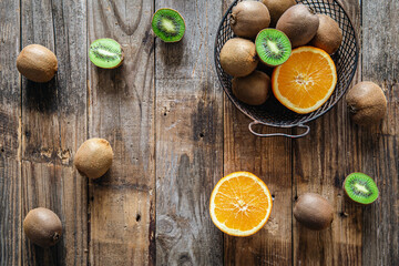 Kiwi and orange fruits on a wooden background, top view.