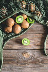 Fruits of kiwi in a mesh bag on a wooden background, top view, rustic style,