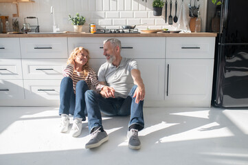 Mature couple resting in the kitchen on the floor and looking peaceful