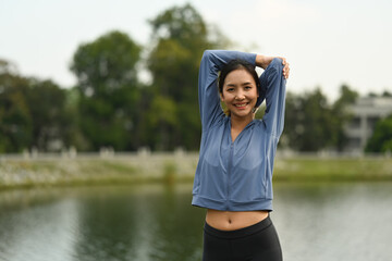 Portrait of sportswoman stretching before running in the park. Fitness, sport and healthy lifestyle concept