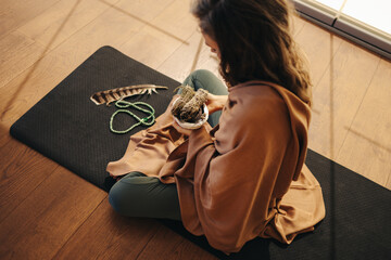 Mature woman meditating with sage smudge sticks at home