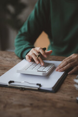 Person pressing white calculator, online store owner checking product order before shipping to customer, selling product through online channels on website and product platform.